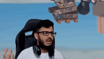 A Man Wearing Glasses And Headphones Is Sitting In A Chair With A Stack Of Boxes Hanging From The Ceiling . GIF