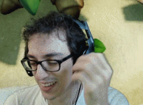 A Man Wearing Glasses And Headphones Is Smiling And Talking On A Cell Phone GIF
