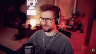 A Man Wearing Glasses And Headphones Is Standing In Front Of A Microphone . GIF