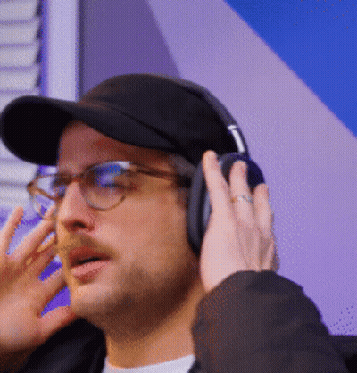 A Man Wearing Glasses And Headphones Is Talking On The Phone GIF