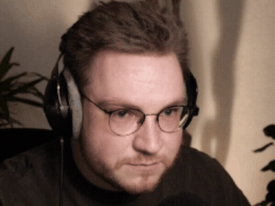 A Man Wearing Glasses And Headphones Looks To His Left GIF
