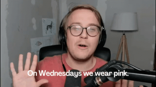 A Man Wearing Glasses And Headphones Says " On Wednesdays We Wear Pink " In Front Of A Microphone GIF