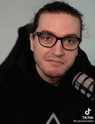 A Man Wearing Glasses Holds A Rode Microphone In His Hand GIF