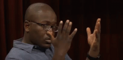 A Man Wearing Glasses Is Covering His Nose With His Hands GIF