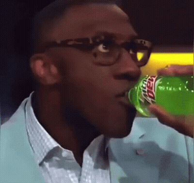 A Man Wearing Glasses Is Drinking A Green Mountain Dew From A Bottle . GIF