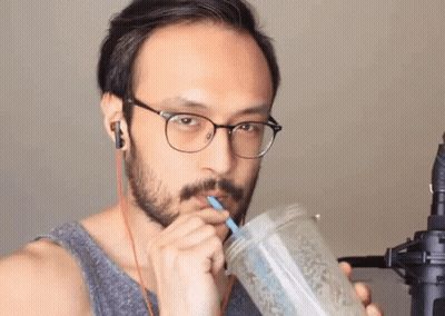 A Man Wearing Glasses Is Drinking From A Mason Jar With A Straw GIF