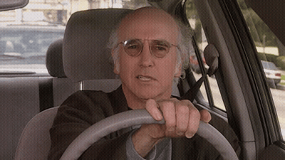 A Man Wearing Glasses Is Driving A Car And Making A Funny Face GIF