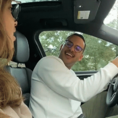 A Man Wearing Glasses Is Driving A Car While A Woman Looks On GIF