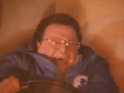 A Man Wearing Glasses Is Holding A Candle In His Hand . GIF