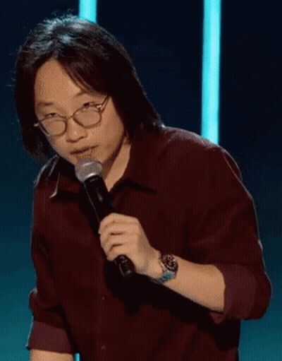 A Man Wearing Glasses Is Holding A Microphone And Says " Good " GIF