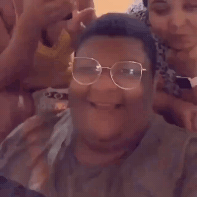 A Man Wearing Glasses Is Laughing While Taking A Selfie With His Friends . GIF