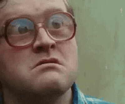 A Man Wearing Glasses Is Making A Funny Face And Looking At The Camera . GIF