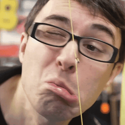 A Man Wearing Glasses Is Making A Funny Face With A String In His Nose GIF