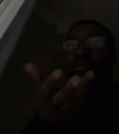 A Man Wearing Glasses Is Making A Funny Face With His Hand . GIF