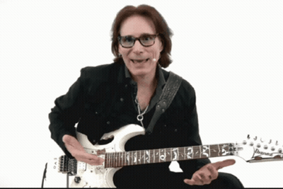 A Man Wearing Glasses Is Playing A White Guitar With The Letters Ibanez On The Neck GIF
