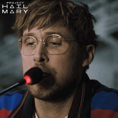 A Man Wearing Glasses Is Singing Into A Microphone With Project Hail Mary Written On The Bottom Right GIF