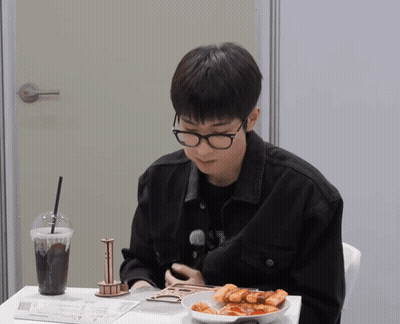 A Man Wearing Glasses Is Sitting At A Table With A Plate Of Food GIF