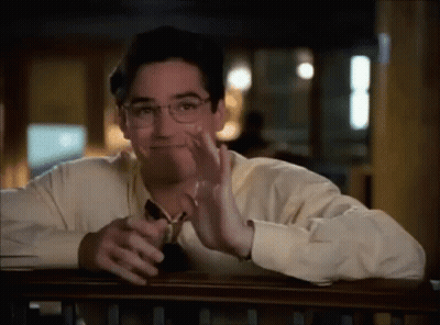 A Man Wearing Glasses Is Sitting At A Table With His Hand On His Face . GIF