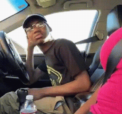 A Man Wearing Glasses Is Sitting In The Driver 'S Seat Of A Car Next To A Bottle Of Water GIF