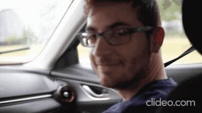 A Man Wearing Glasses Is Sitting In The Driver 'S Seat Of A Car With Clideo.com Displayed On The Bottom GIF