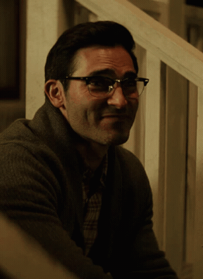 A Man Wearing Glasses Is Sitting On A Set Of Stairs And Smiling GIF