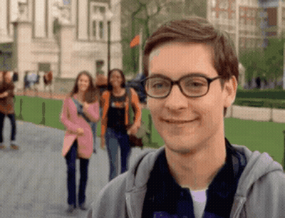 a man wearing glasses is smiling in front of a blurry group of people