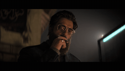 A Man Wearing Glasses Is Smoking A Cigarette In Front Of A Wall With Arabic Writing On It GIF