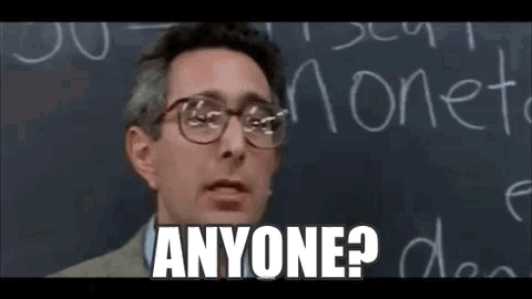 A Man Wearing Glasses Is Standing In Front Of A Blackboard And Says `` Anyone ? '' . GIF