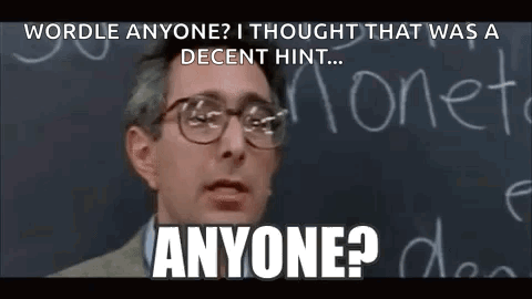 A Man Wearing Glasses Is Standing In Front Of A Blackboard With The Words `` Wordle Anyone '' Written On It . GIF