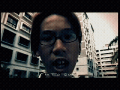 A Man Wearing Glasses Is Standing In Front Of A Building And Says " Xxx " GIF