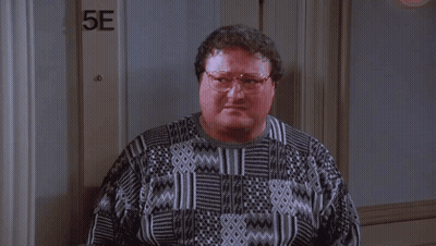 A Man Wearing Glasses Is Standing In Front Of A Door That Says 5E . GIF