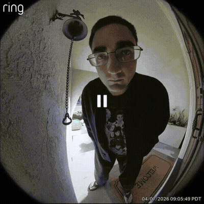 A Man Wearing Glasses Is Standing In Front Of A Door With A Welcome Mat GIF