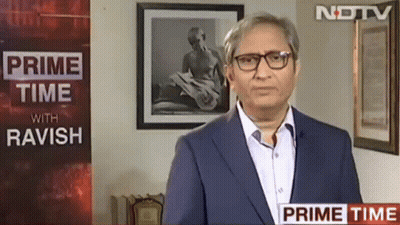 A Man Wearing Glasses Is Standing In Front Of A Sign That Says Prime Time With Ravish GIF