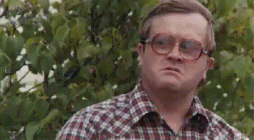 A Man Wearing Glasses Is Standing In Front Of A Tree . GIF