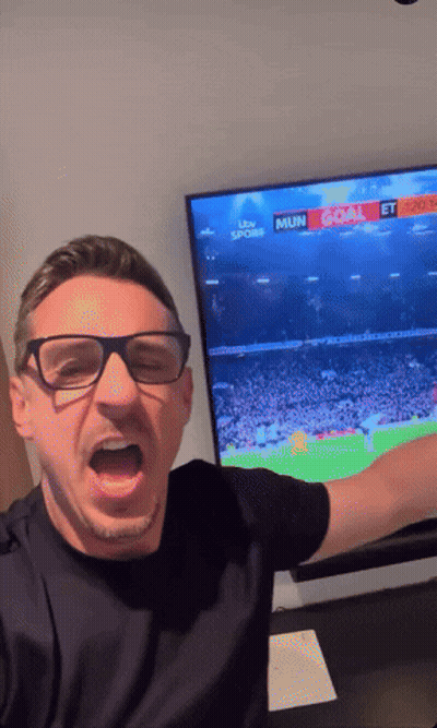 A Man Wearing Glasses Is Standing In Front Of A TV That Says ' Mun Goal ' On It GIF