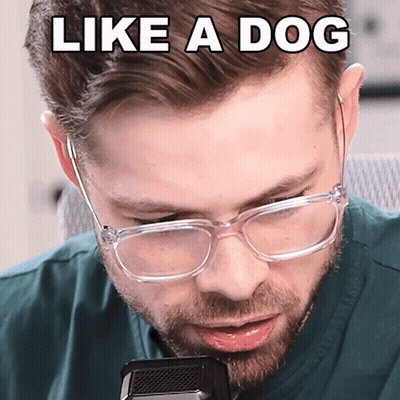 A Man Wearing Glasses Is Talking Into A Microphone With The Words Like A Dog Above His Head GIF