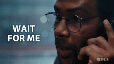 A Man Wearing Glasses Is Talking On A Cell Phone And The Words Wait For Me Are Behind Him GIF