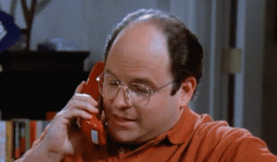 A Man Wearing Glasses Is Talking On A Red Phone . GIF