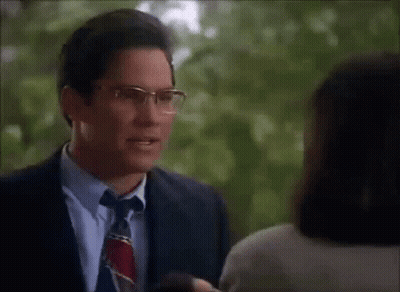 A Man Wearing Glasses Is Talking To A Woman GIF