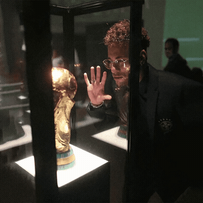 A Man Wearing Glasses Looks At A Trophy In A Case GIF