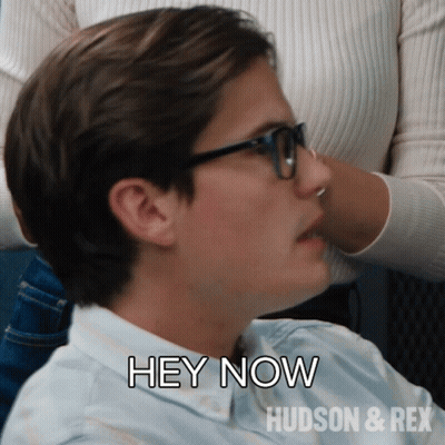 A Man Wearing Glasses Says " Hey Now " In Front Of A Woman GIF