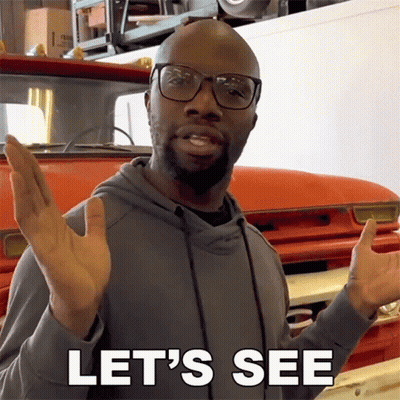 A Man Wearing Glasses Says Let 'S See While Standing In Front Of A Red Truck GIF