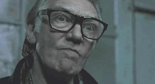 A Man Wearing Glasses Says Me !!! In A Dark Room GIF