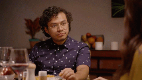 A Man Wearing Glasses Sits At A Table Eating Food GIF