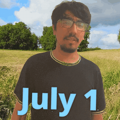 A Man Wearing Glasses Stands In A Field With The Date July 1 On His Shirt GIF