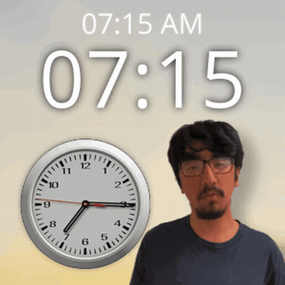 A Man Wearing Glasses Stands In Front Of A Clock That Says 7:15 GIF