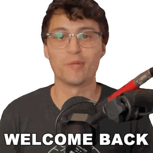 A Man Wearing Glasses Stands In Front Of A Microphone Saying Welcome Back Sticker