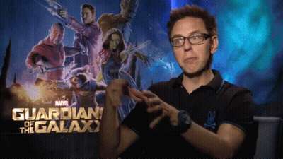 A Man Wearing Glasses Stands In Front Of A Poster For Guardians Of The Galaxy GIF