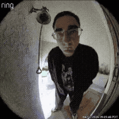 A Man Wearing Glasses Stands In Front Of A Ring Doorbell Camera GIF