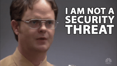 A Man Wearing Glasses Stands In Front Of A Sign That Says I Am Not A Security Threat GIF